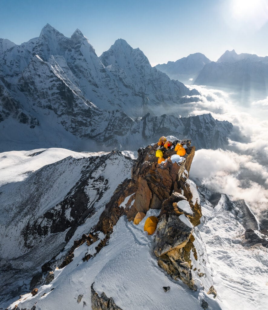 a group of people sitting on top of a snow covered mountain