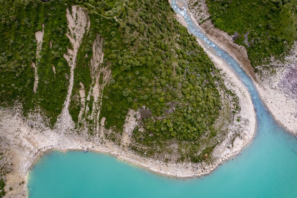 an aerial view of a river running through a lush green forest