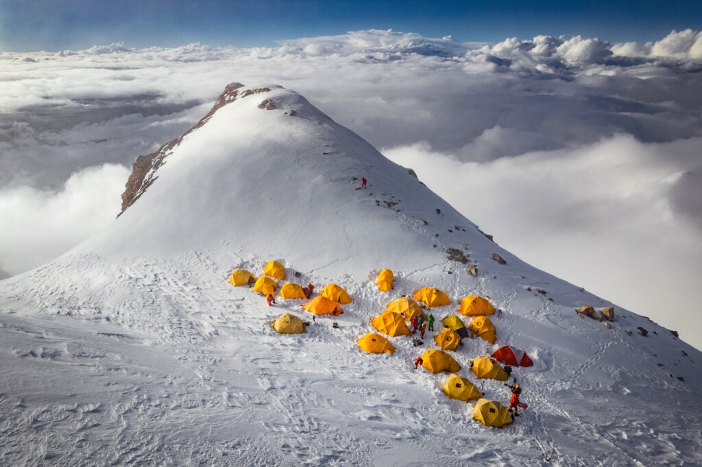a group of people standing on top of a snow covered mountain