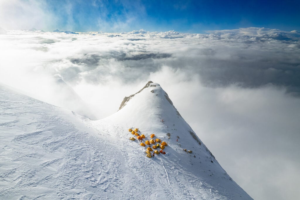 a group of people standing on top of a snow covered mountain