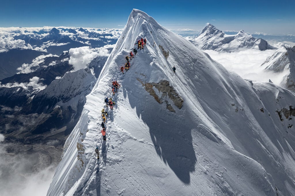 a group of people climbing up the side of a snow covered mountain