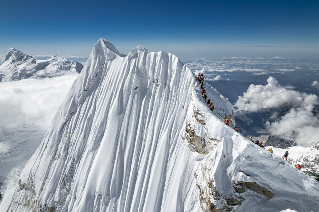 a group of people climbing up the side of a snow covered mountain
