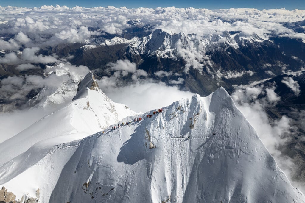 a group of people climbing up the side of a snow covered mountain