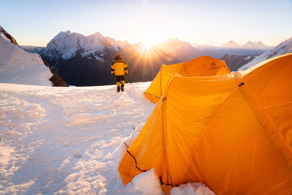 a person standing next to a tent in the snow