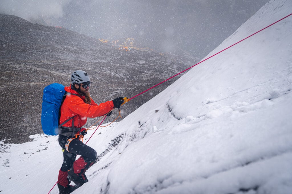 a man with a backpack climbing up a snowy mountain