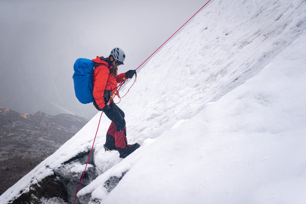 a man climbing up the side of a snow covered mountain