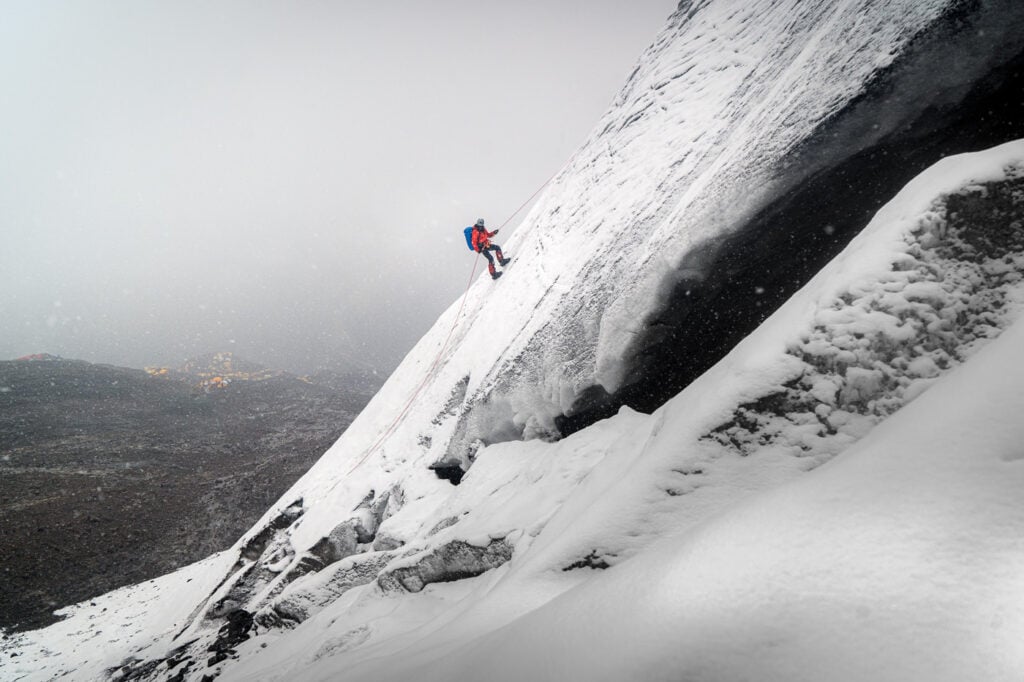 a man climbing up the side of a snow covered mountain