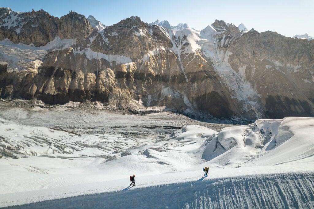 a couple of people riding skis down a snow covered slope