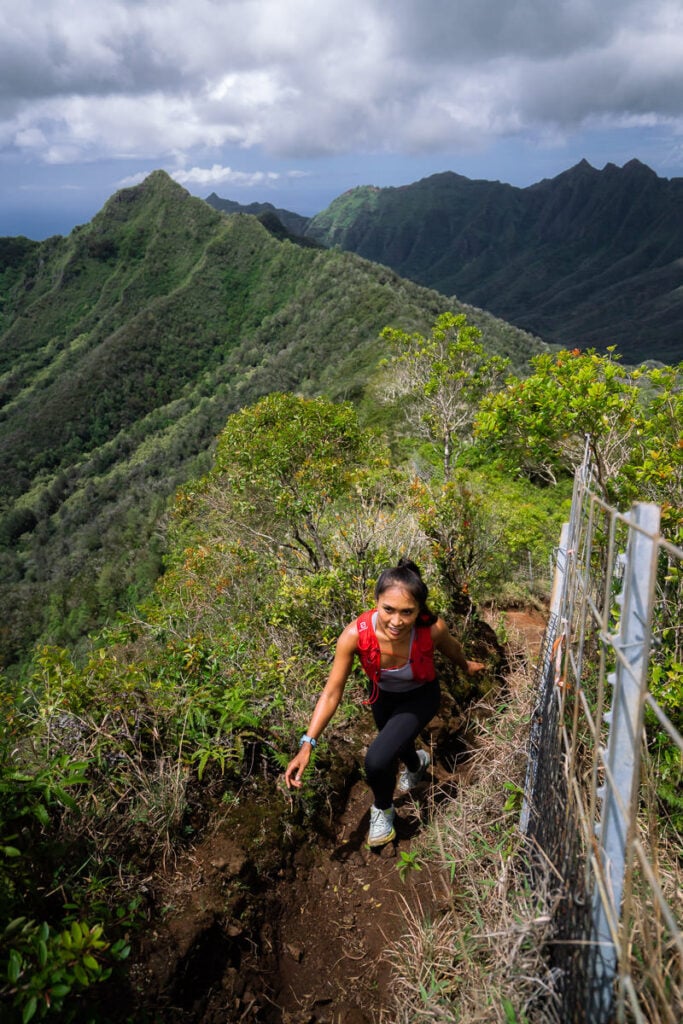 a woman hiking up a steep hill in the mountains.
