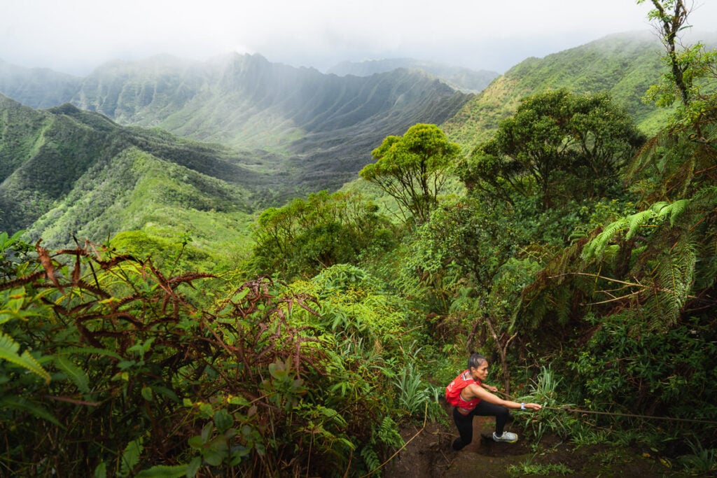 a woman in a red shirt is sitting on a trail.